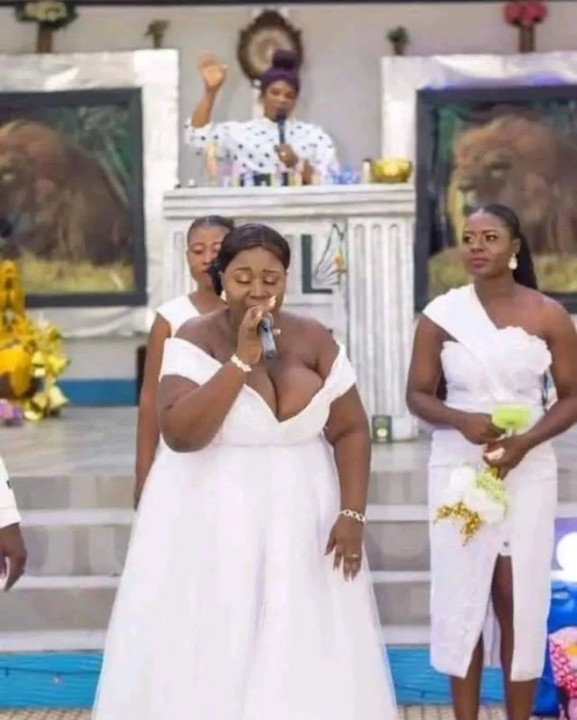 a fat black woman with white long dress singing in the church with her breasts